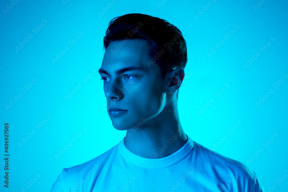 Look. Handsome caucasian man's portrait isolated on blue studio background in neon, monochrome. Beautiful male model. Concept of human emotions, facial expression, sales, ad, fashion and beauty. Look. Handsome caucasian man's portrait isolated on blue studio background in neon, monochrome. Beautiful male model. Concept of human emotions, facial expression, sales, ad, fashion and beauty.