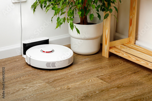 Schilderij op canvas White robotic vacuum cleaner on wooden floor