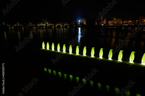 Prague, Czech Republic - January 1 2021: Sculptures of 34 lighted yellow pinguins by Cracking Art Group were installed in Prague in 2008. 