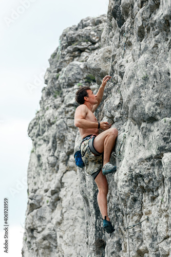 The rock climber climbs up the rock.