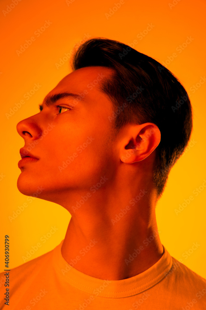 Hero. Handsome caucasian man's portrait isolated on orange studio background in neon, monochrome. Beautiful male model. Concept of human emotions, facial expression, sales, ad, fashion and beauty. Hero. Handsome caucasian man's portrait isolated on orange studio background in neon, monochrome. Beautiful male model. Concept of human emotions, facial expression, sales, ad, fashion and beauty.
