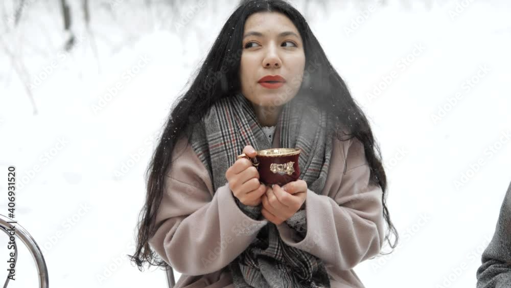 Pretty hispanic or asian female drinking hot tea from a cup in winter forest. Cozy Winter picnic with croissants and firends, enjoying aesthetics, natural calmness, winter snowy nature, cold weather Pretty hispanic or asian female drinking hot tea from a cup in winter forest. Cozy Winter picnic with croissants and firends, enjoying aesthetics, natural calmness, winter snowy nature, cold weather