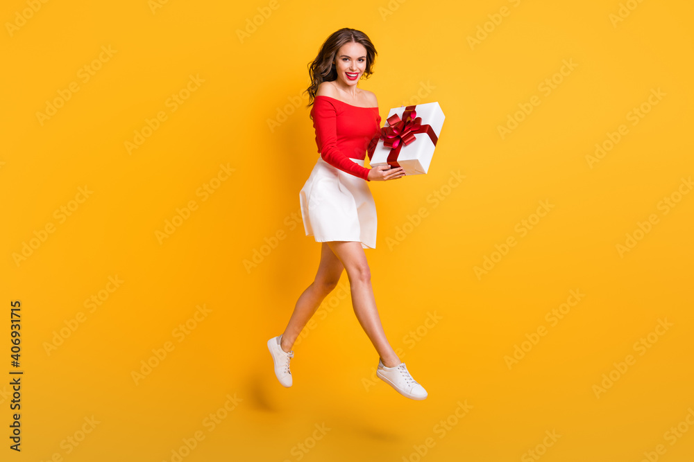 Full length body size photo girl keeping wrapped gift box laughing isolated on vibrant yellow color background