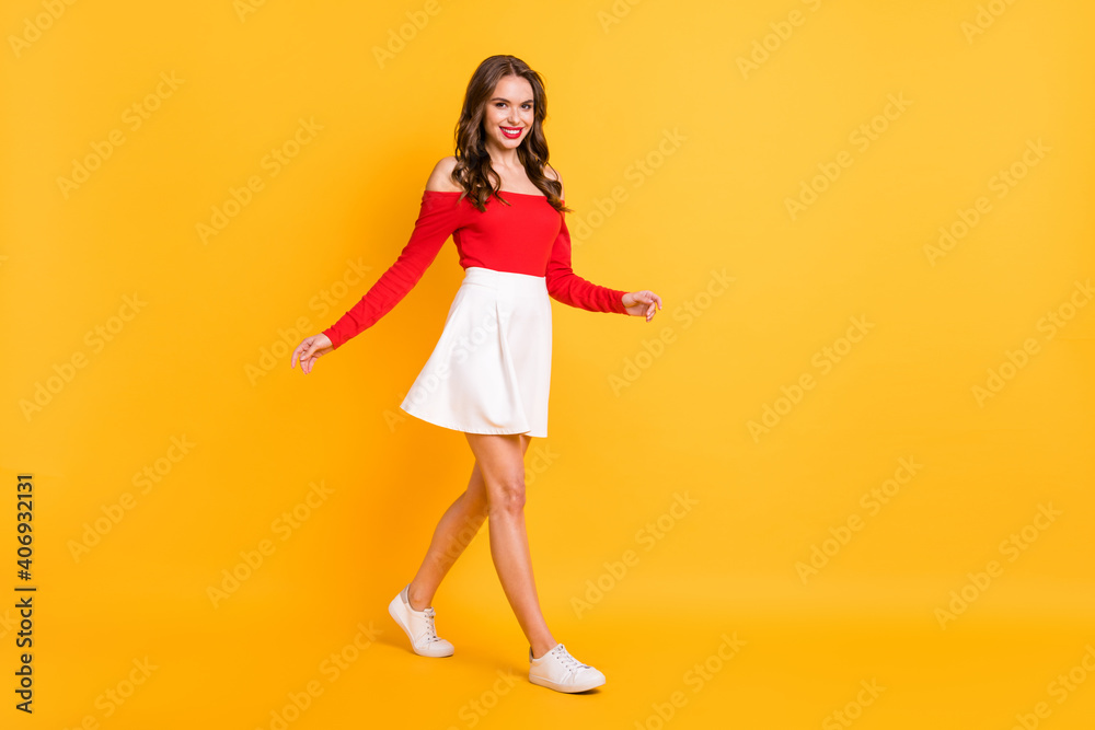 Full length body size photo girl smiling walking forward in mini skirt cheerful isolated on vivid yellow color background Full length body size photo girl smiling walking forward in mini skirt cheerful isolated on vivid yellow color background