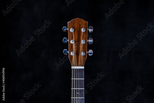 acoustic guitar head with chrome tuning pegs and fretboard on isolated black background