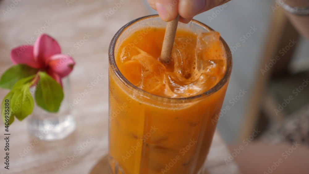 Close up of paper straw stirring fresh carrot juice with ice Close up of paper straw stirring fresh carrot juice with ice