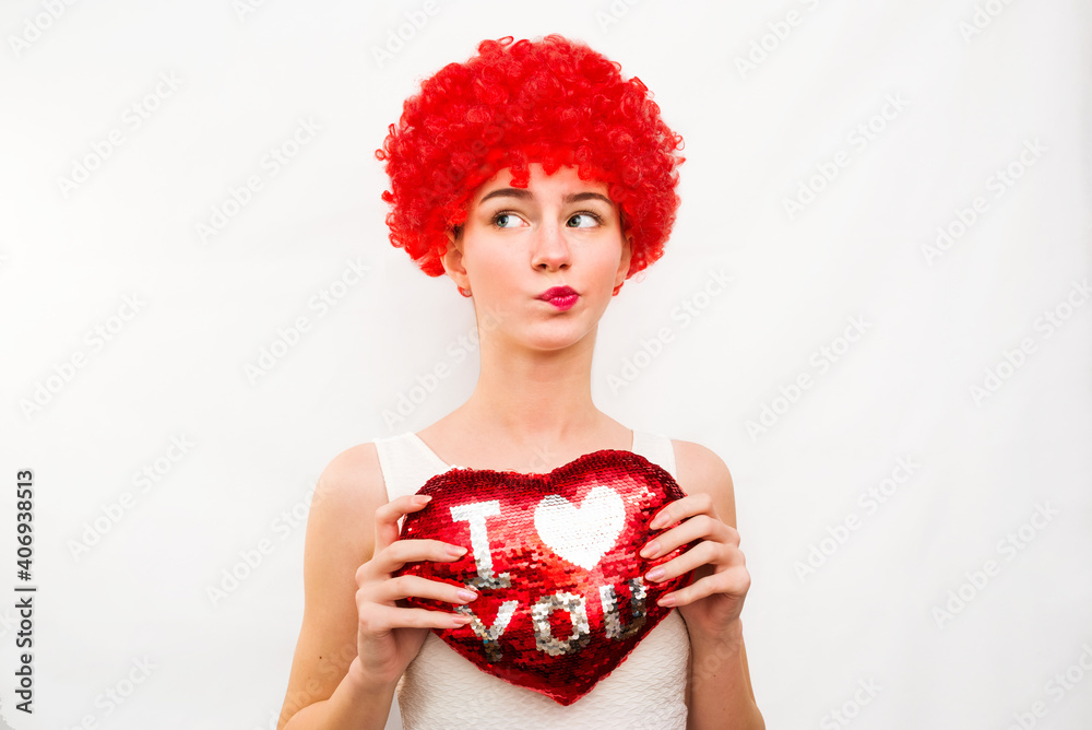 A girl in a red wig holds a heart in her hands. concept for Valentine's Day, Holiday, Birthday A girl in a red wig holds a heart in her hands. concept for Valentine's Day, Holiday, Birthday