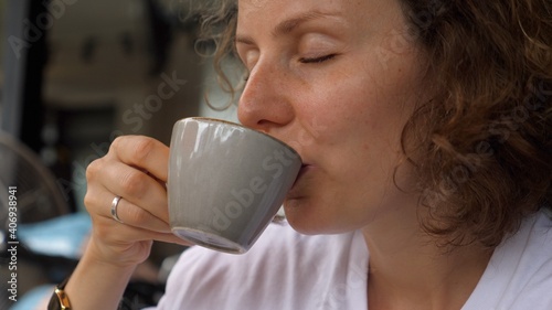 Caucasian girl enjoys a sip of hot vegan cappuccino. Simple pleasures concept.