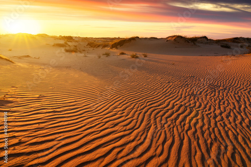 Sunset over the sand dunes in the desert. Arid landscape of the Sahara desert