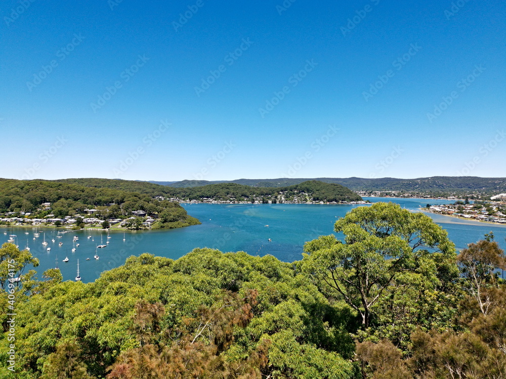 Beautiful view of a bay full of boats with tall tree in the foreground and mountains, trees and deep blue sky in the background, Allen Strom Lookout, Brisbane Water, Rocky Point Trail, New South Wales