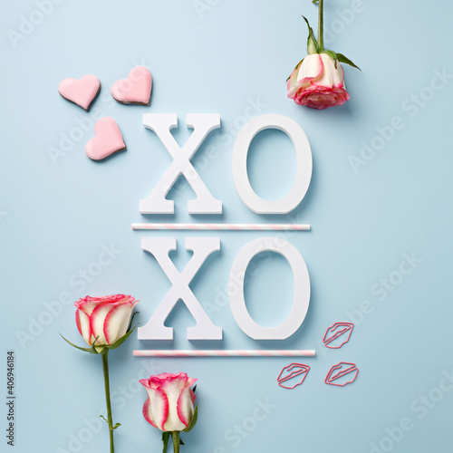 Phrase xoxo made with rose flowers and heart shaped cookies on pastel pink background. Minimal kisses and hugs concept.  Valentines day, 8th March, love or wedding layout. Top view, flat lay.