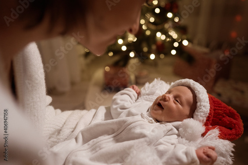 Happy young mother posing with newborn son under Christmas tree. High quality photo