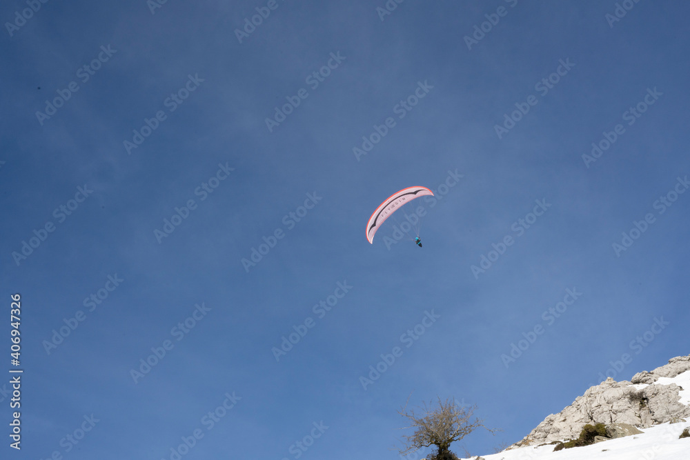 Paraglider flying over the mountains in winter Paraglider flying over the mountains in winter