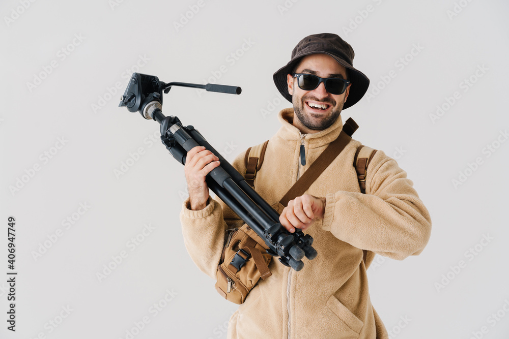 Joyful young photographer smiling while posing with tripod Joyful young photographer smiling while posing with tripod