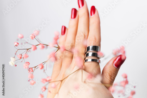 Soft gentle photo of woman hand with big ring red manicure hold cute little pink dried flowers isolated on white background  spring mood.