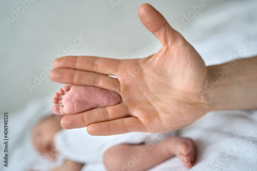 Baby's feet in the father's hands, the foot of a newborn baby, a little baby lies in the crib. . High quality photo