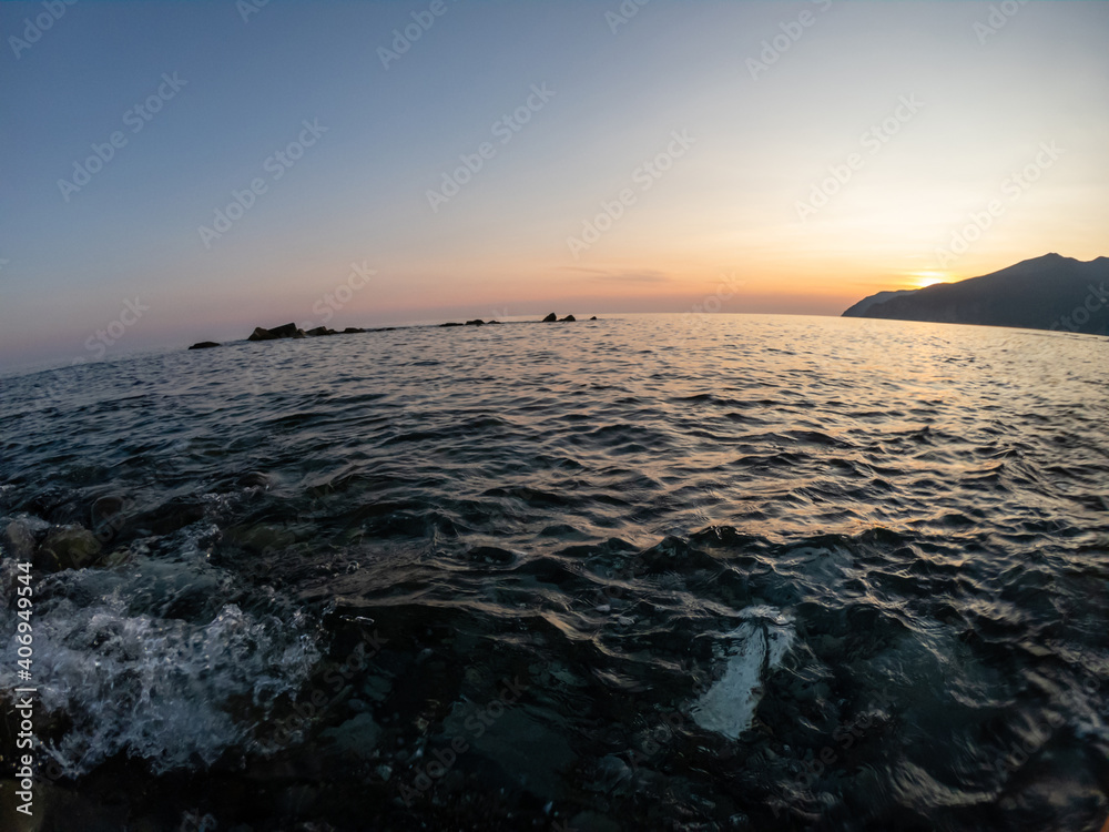 sunset over the sea. the sun is hiding behind the mountain sunset over the sea. the sun is hiding behind the mountain