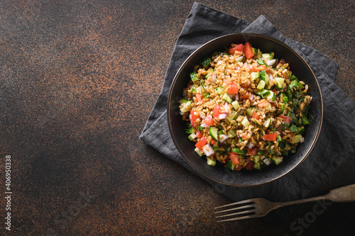 Fotografija Salad of whole grain cereal spelt with seasonal vegetables, tomato, cucumber in bowl on brown background