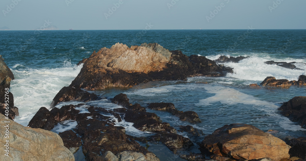 Sea waves splash against rock on island