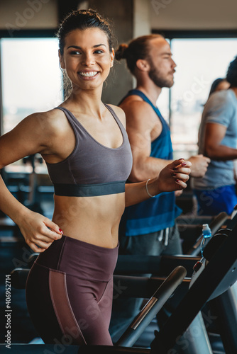 Fototapeta Naklejka Na Ścianę i Meble -  Group of young people running on treadmills in sport gym