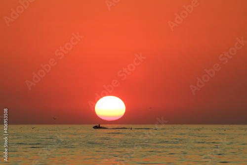 man enjoys life while riding a water bike on the background of a sunset in the sea