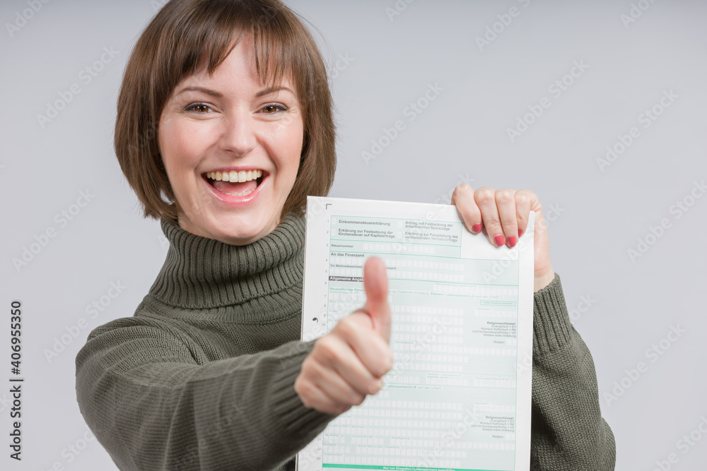 happy woman presents a tax declaration form and shows thumbs up happy woman presents a tax declaration form and shows thumbs up
