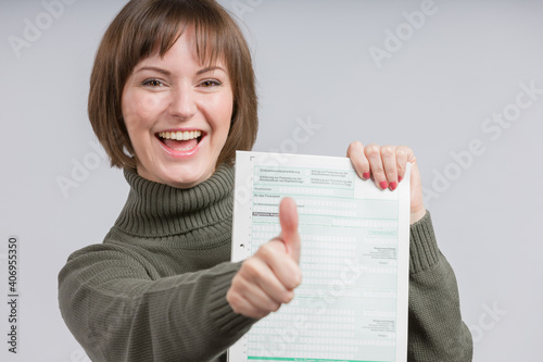 happy woman presents a tax declaration form and shows thumbs up photo