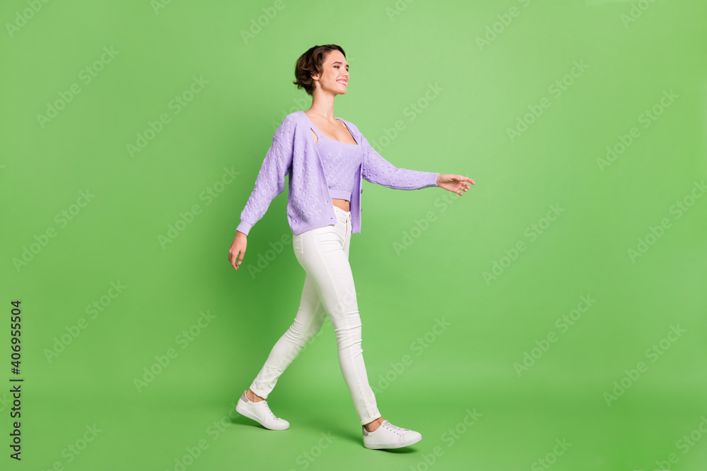 Full size profile photo of adorable positive lady walking look empty space isolated on green color background Full size profile photo of adorable positive lady walking look empty space isolated on green color background