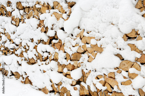 stack of wooden logs covered with fresh snow