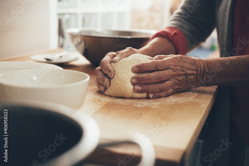 Female hands preparing homemade bread. Elderly woman in kitchen knead the dough until it is smooth.