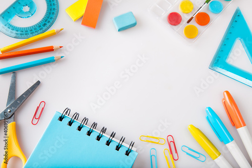 Children education, accessories, school supplies, colored pencils and a notebook in trendy colors on a white background with space for your text. Schoolchildren creativity concept and back to school 