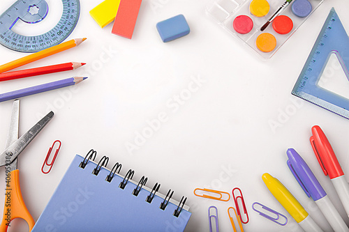 Children education, accessories, school supplies, colored pencils and a notebook in trendy colors on a white background with space for your text. Schoolchildren creativity concept and back to school 