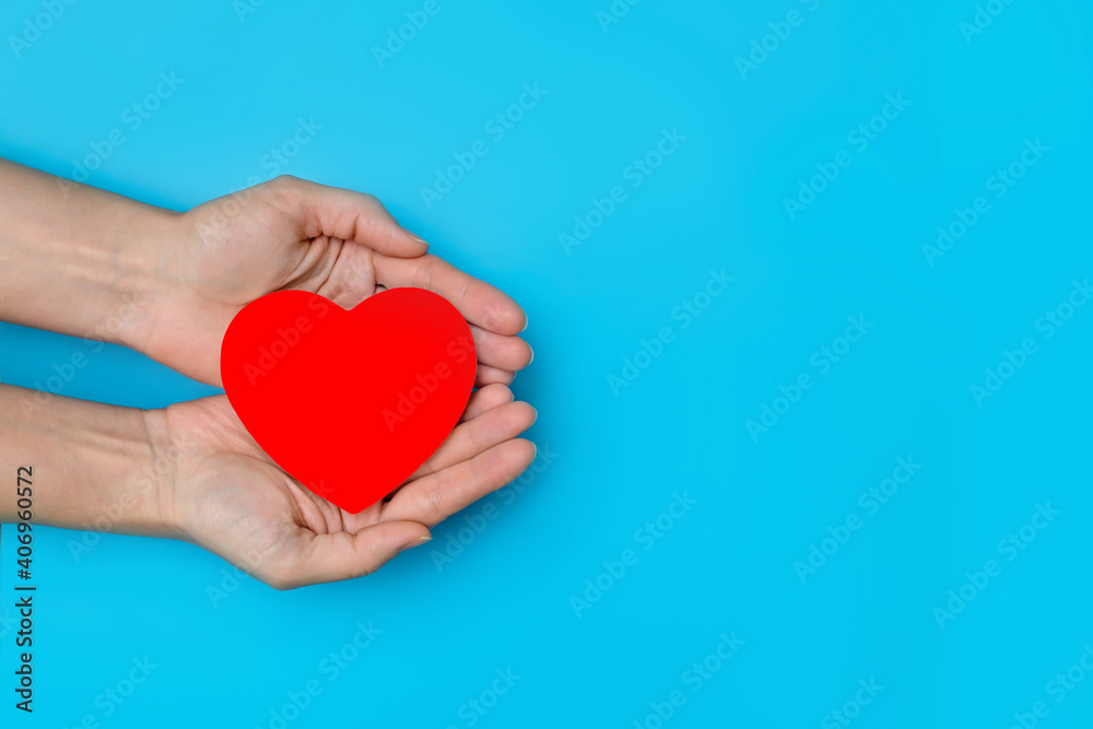Fototapeta premium heart in the hands of a person on a blue background copy space, the concept of support, kindness and charity