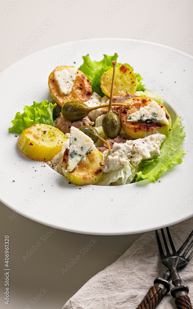 Quick and healthy food recipes. Salad with grilled zucchini, vegetables, herbs, turkey sous vide meat, blue cheese and capers on white plate. Mediterranean dish recipes. Vertical shot Quick and healthy food recipes. Salad with grilled zucchini, vegetables, herbs, turkey sous vide meat, blue cheese and capers on white plate. Mediterranean dish recipes. Vertical shot