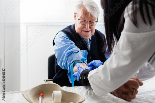 Nurse drawing blood from an elderly man in his home. Home care.