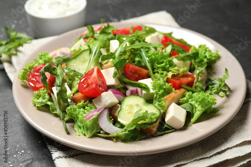 Delicious salad with meat, arugula and vegetables on black table, closeup