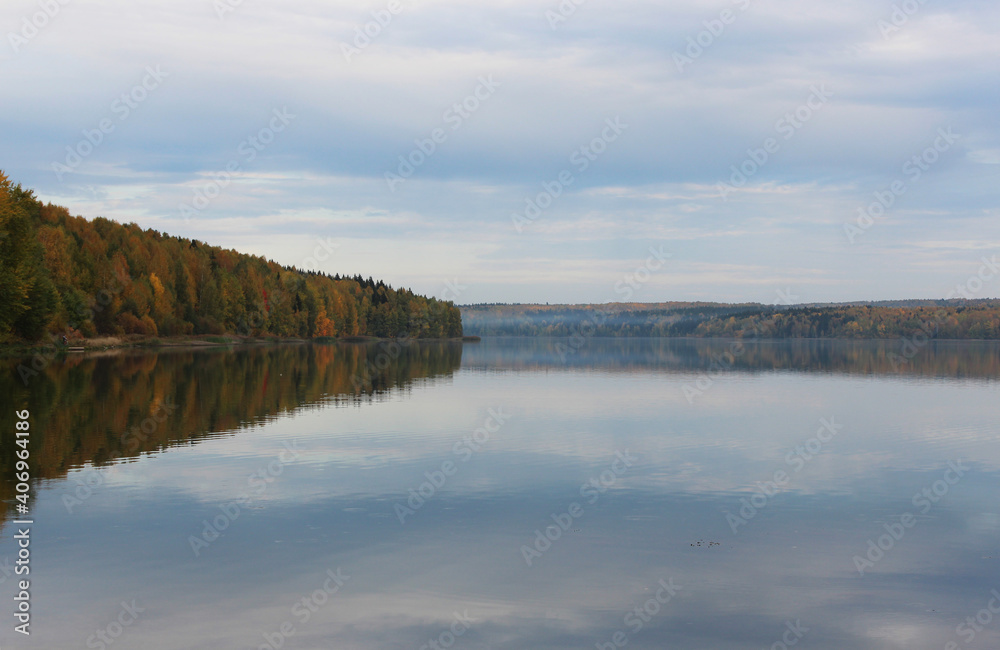the autumn forest is reflected in the lake