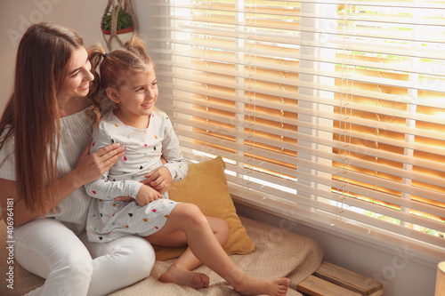 Happy mother with little daughter near window at home photo
