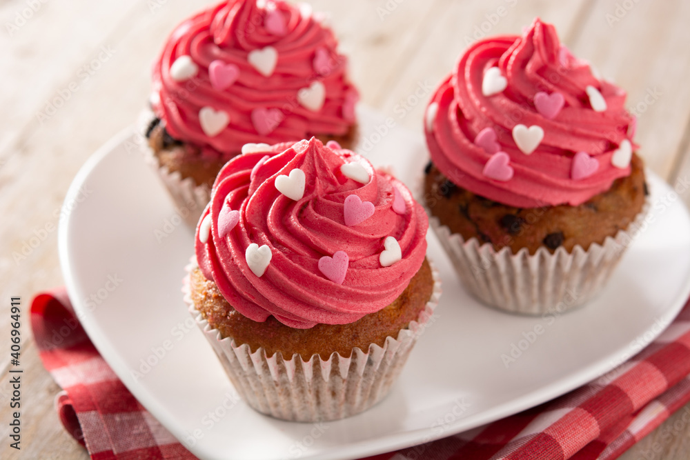 Cupcakes decorated with sugar hearts for Valentine's Day on wooden table