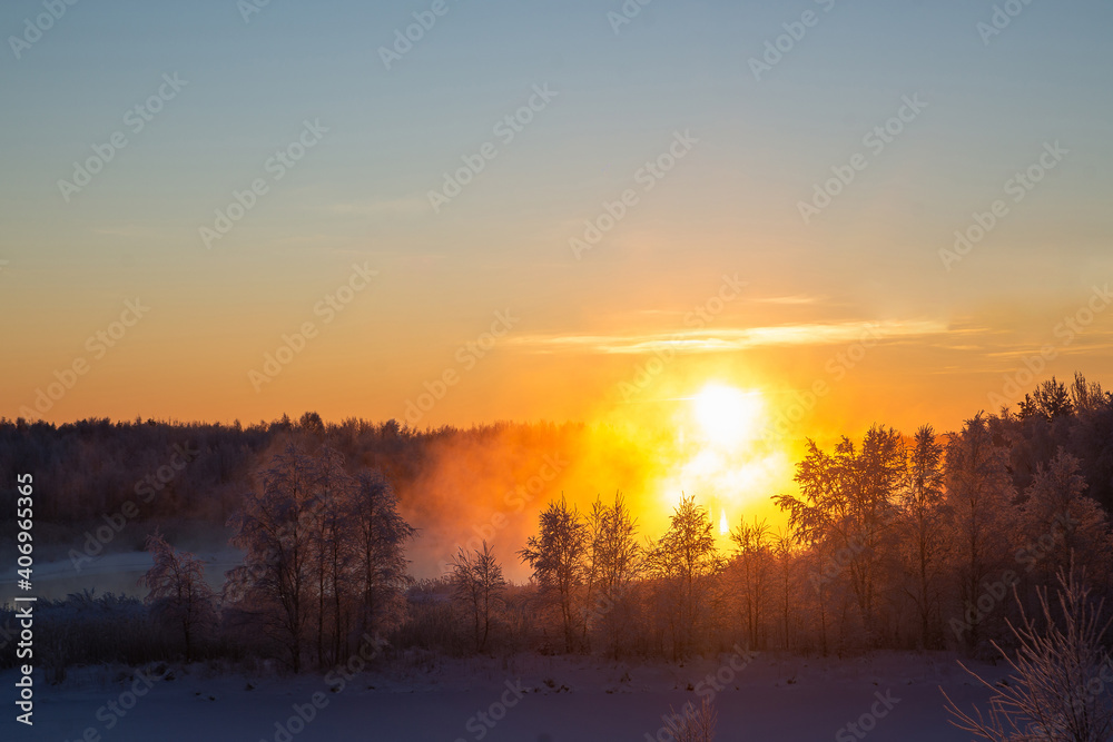 Fototapeta Wspaniały zimowy krajobraz z mgłą oświetloną pomarańczowym światłem zimowego słońca w mroźną pogodę w lesie