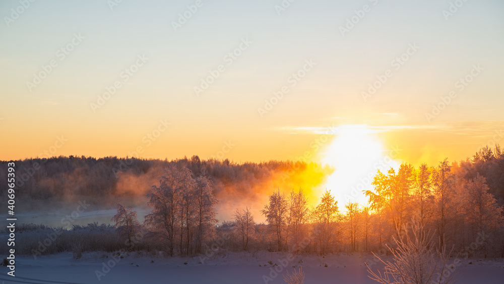Fototapeta Wspaniały zimowy krajobraz z mgłą oświetloną pomarańczowym światłem zimowego słońca w mroźną pogodę w lesie