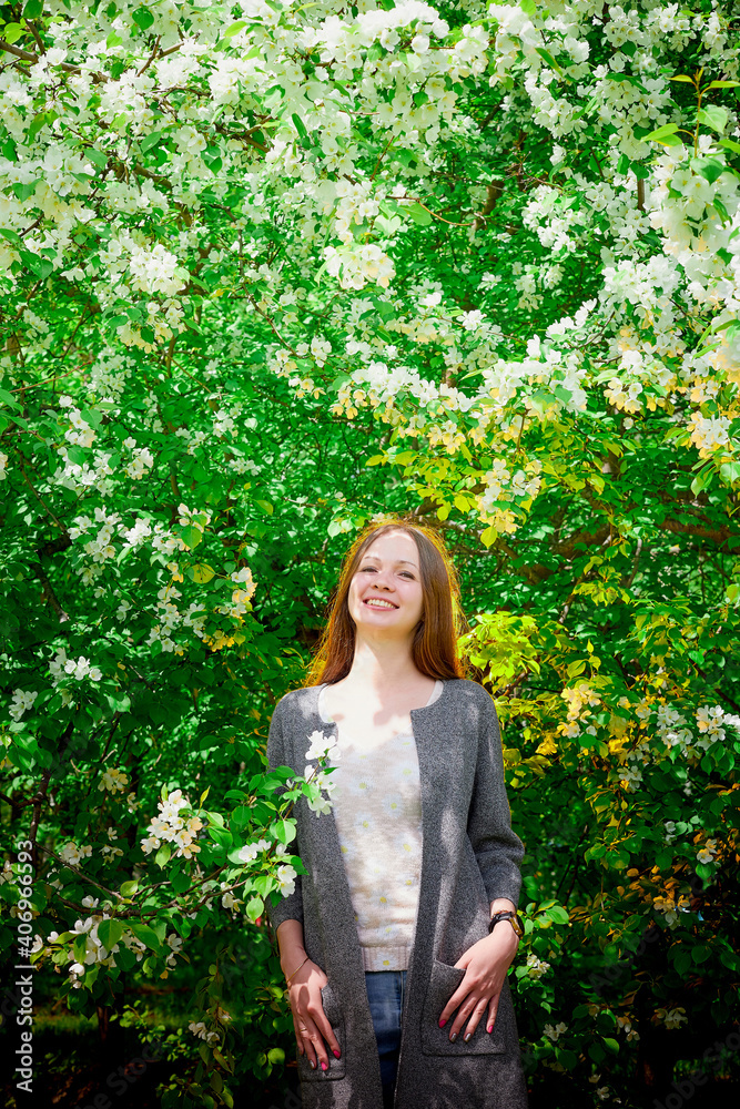 Outdoor portrait of a beautiful young girl near blossom apple trees with white flowers. Outdoor portrait of a beautiful young girl near blossom apple trees with white flowers.