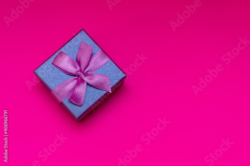 Gift box with ribbon on a pink background. Composition for Valentine's Day. Flat lay, copy space, top view.