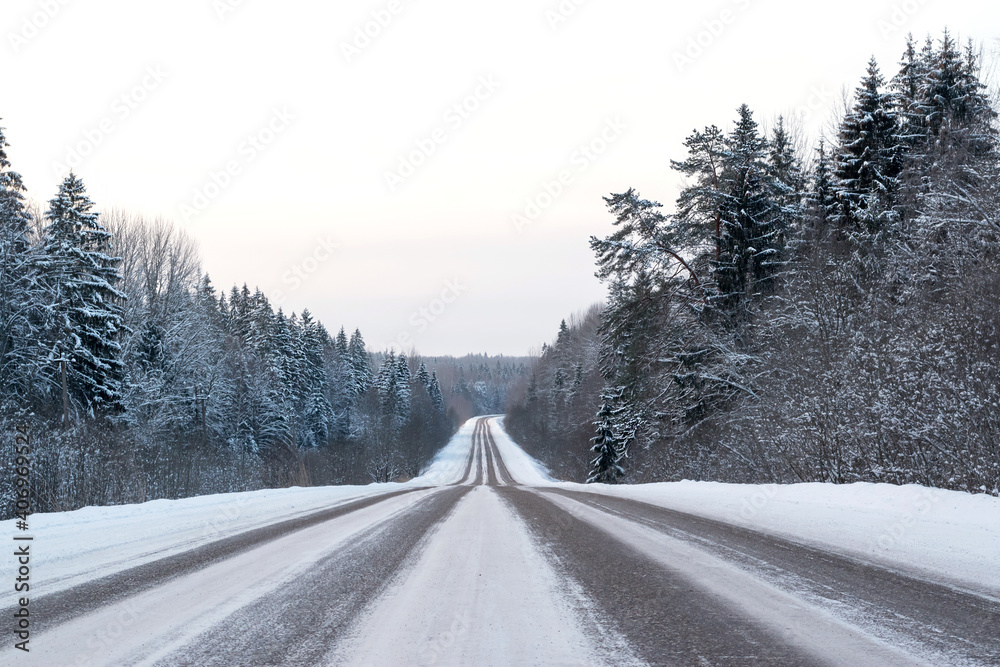 Snow-covered road along the forest in winter. Snow-covered road along the forest in winter.