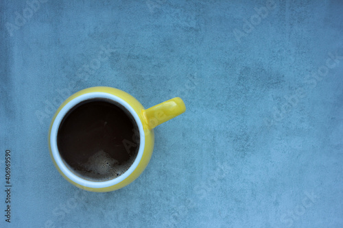 Yellow cup of coffee on gray concrete background. Overhead view