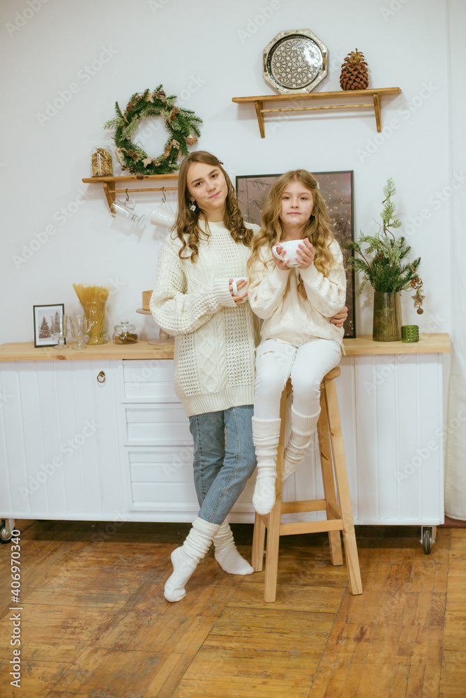 girls in warm light knitted sweaters in the kitchen with cups of warm cocoa girls in warm light knitted sweaters in the kitchen with cups of warm cocoa
