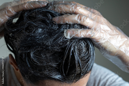 Closeup woman hands dyeing hair. Middle age woman colouring dark hair with gray roots at home