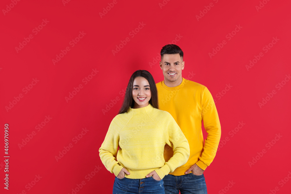 Obraz premium Happy couple wearing yellow warm sweaters on red background
