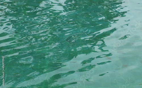 Green water surface of swimming pool. © Amphon