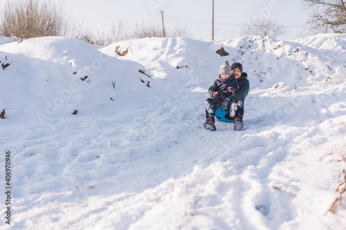 Happy dad and little boy playing with snow sled. Father and son sledding during winter holiday.